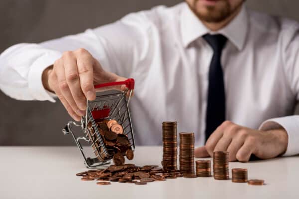 Mini shopping cart with coins spilling out, symbolizing financial management or saving money.